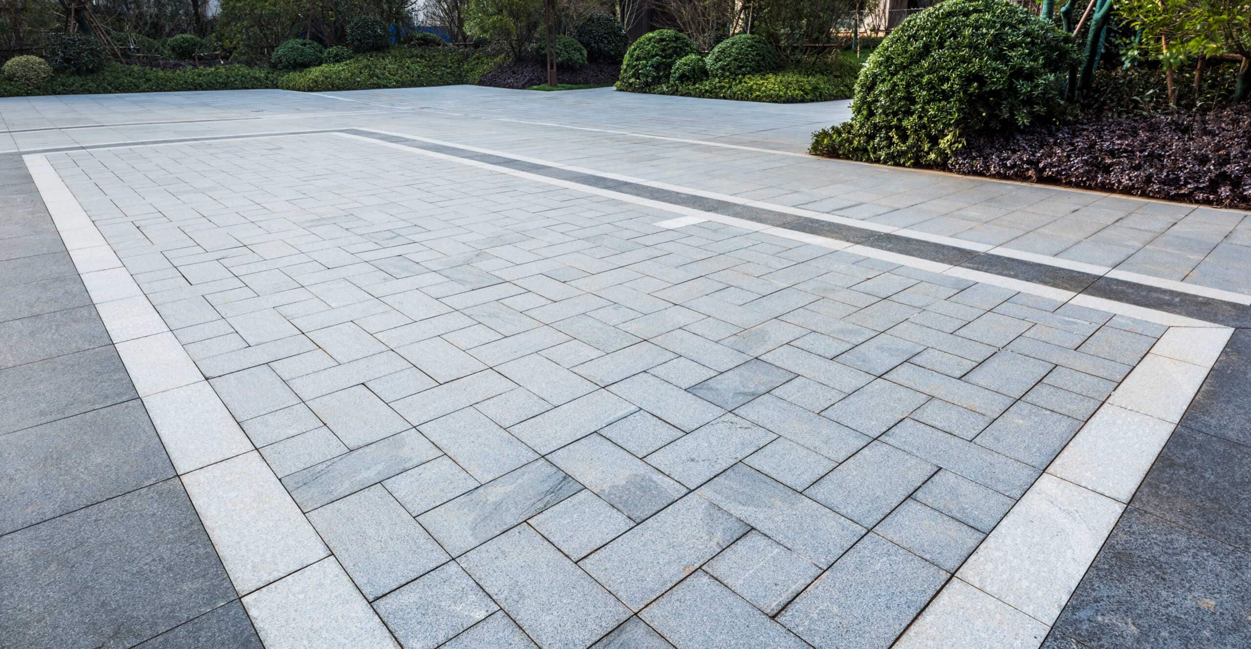 a grey paver patio driveway surrounded by evergreen landscaping
