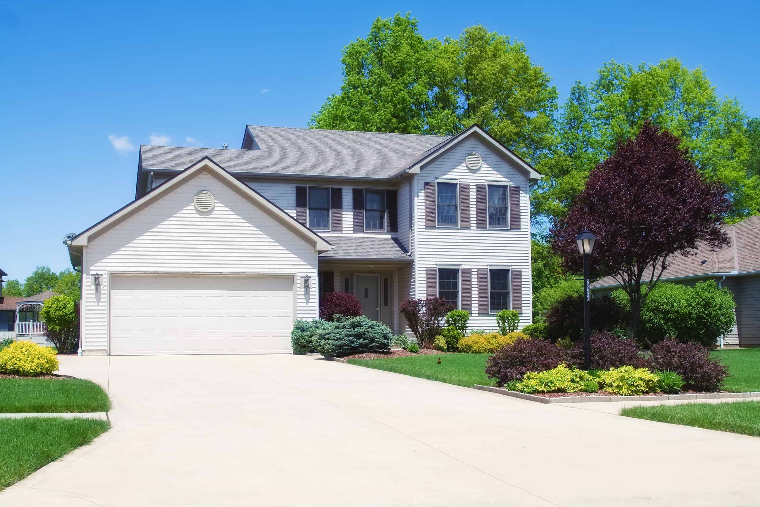 a home set back from the road with a wide concrete driving leading to the garage door
