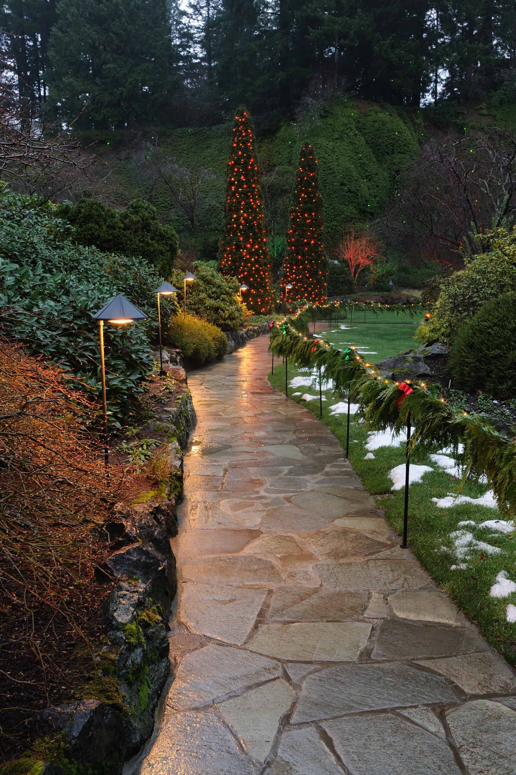 A paver walkway flanked by landscaping lights and seasonal decorations