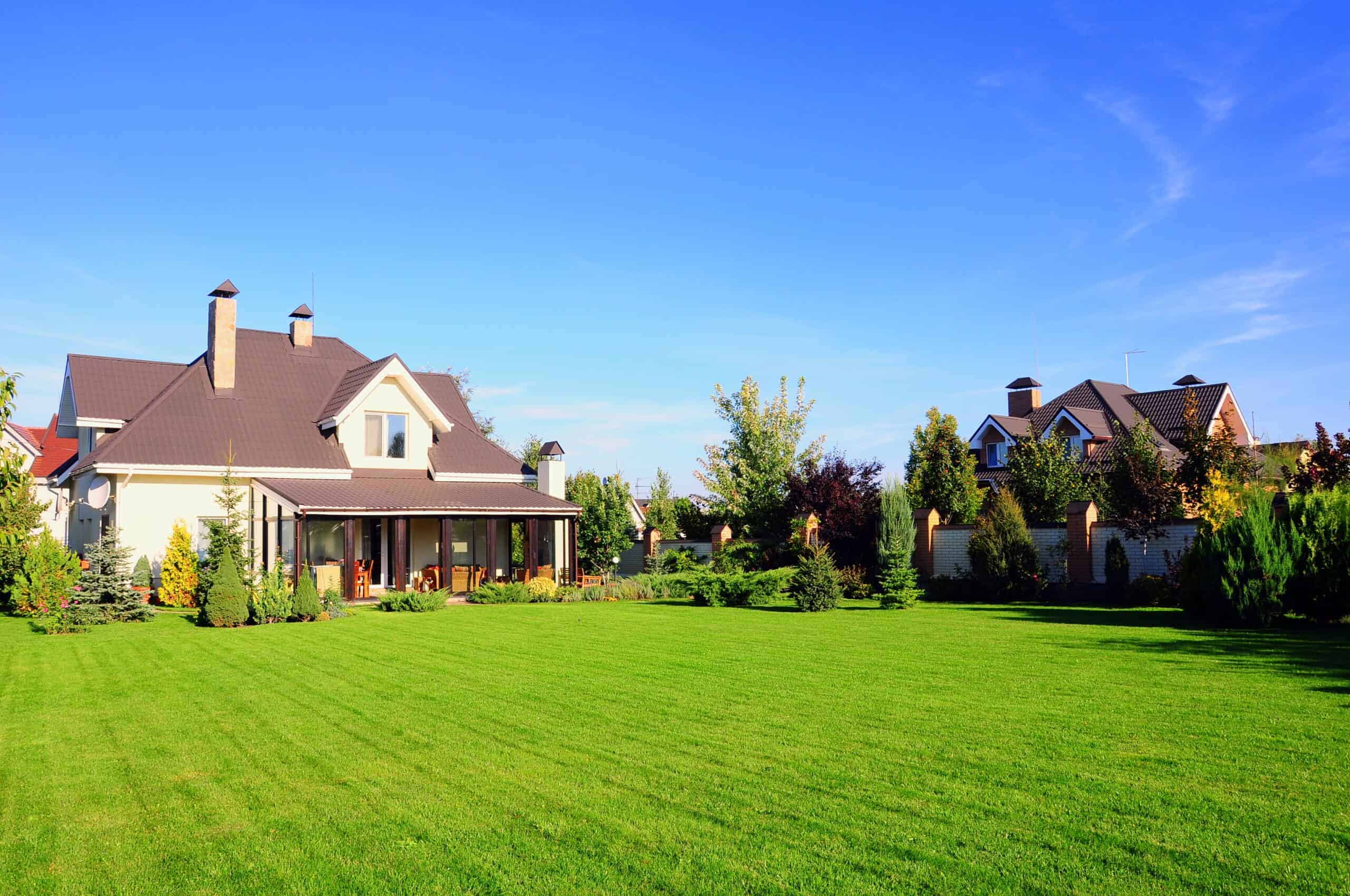 a home with a large front porch and sprawling front yard next door to another house across the fence