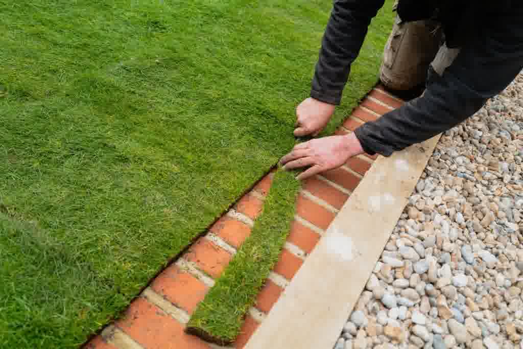 An expert landscaper trimming the edges of new sod to ensure a perfect fit.