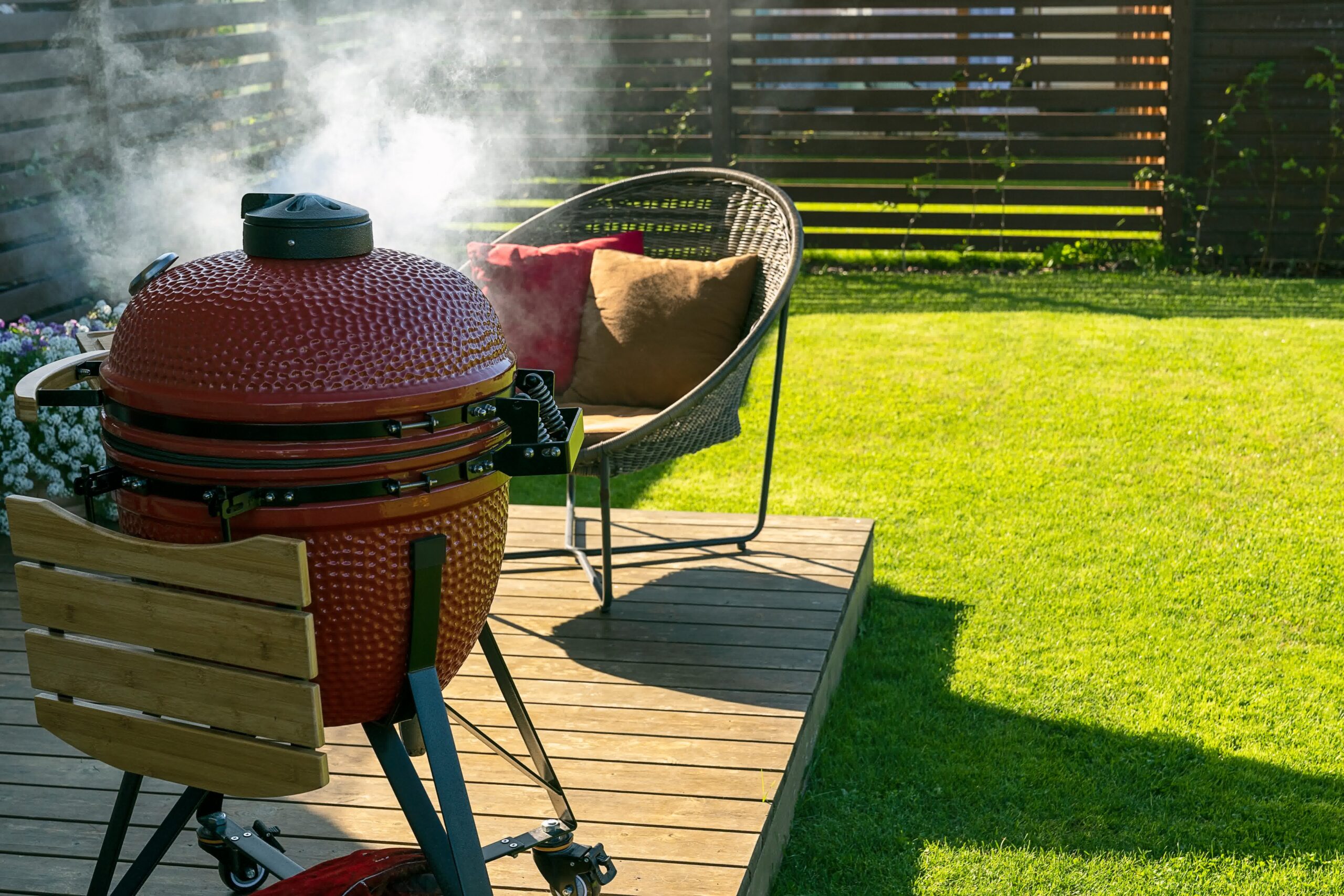 A simple and sturdy deck with a smoker and chair.