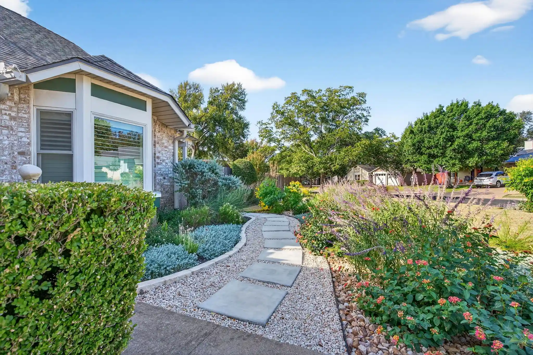 Modern paver patio with stone walkway and landscaped garden featuring shrubs and gravel edging for curb appeal.