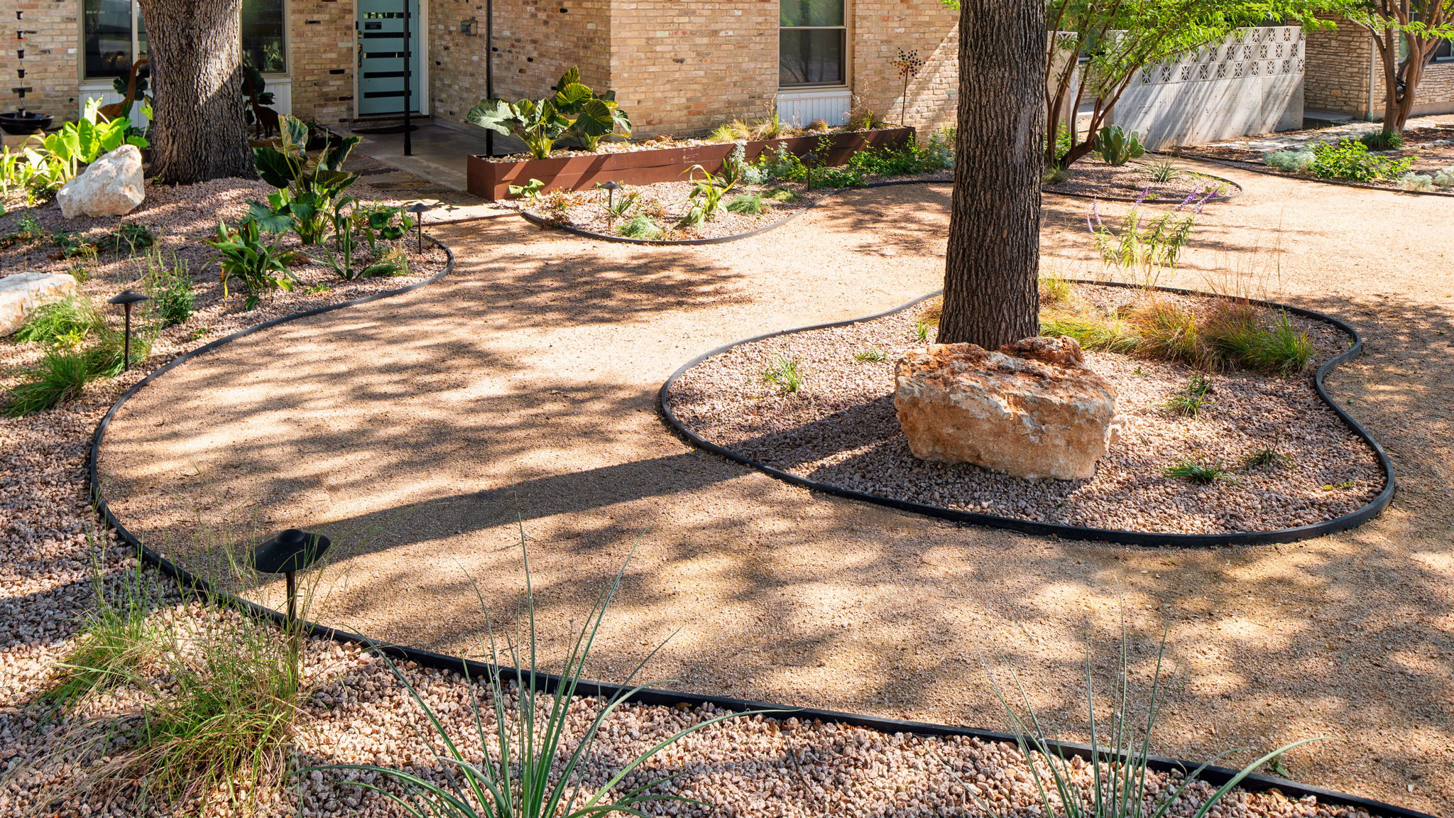 Contemporary landscape with decomposed granite paths and drip irrigation installation providing efficient water flow for plants.